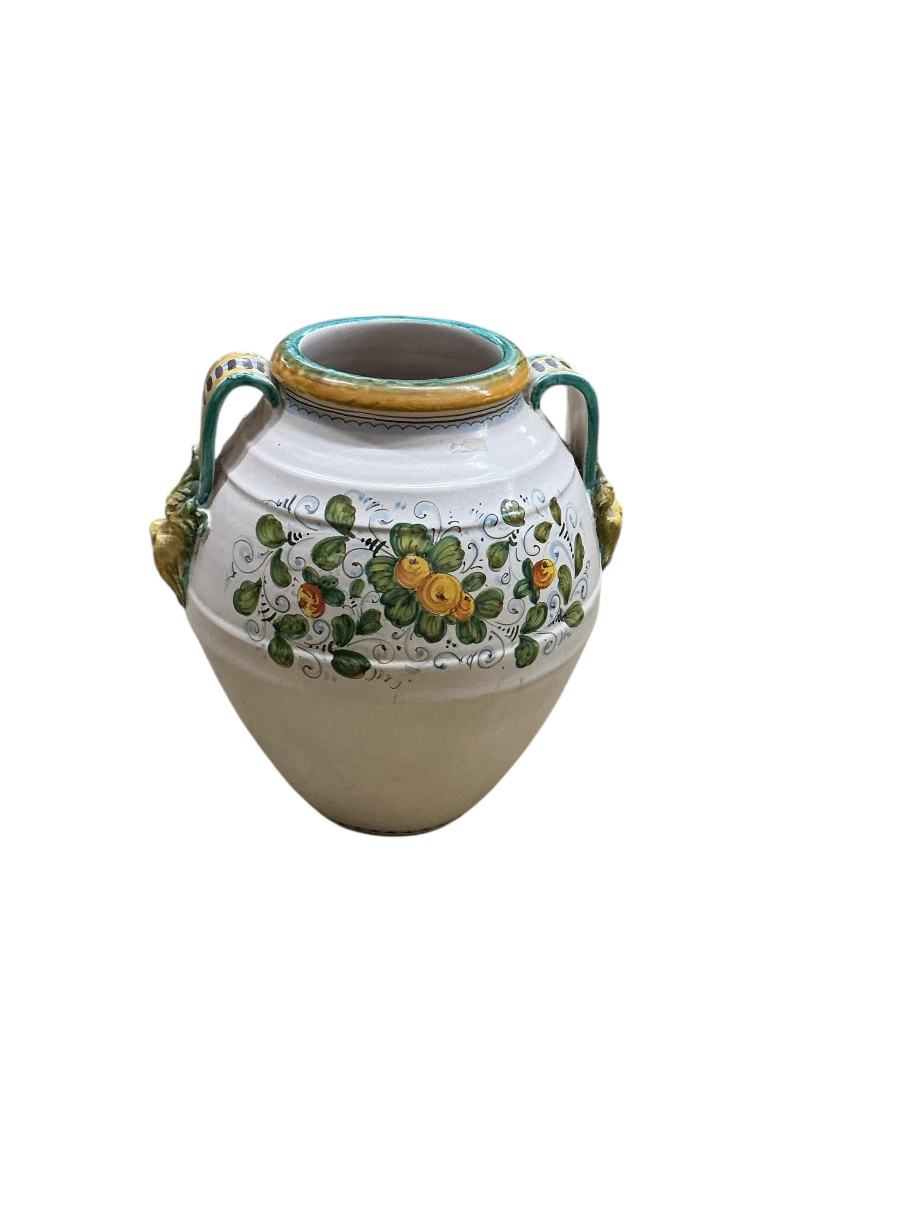A large Italian Maiolica wine jar with spigot hole, twin handles with grotesque masks, all-over decorated with fruiting foliage and a central armorial cartouche, height 48cm